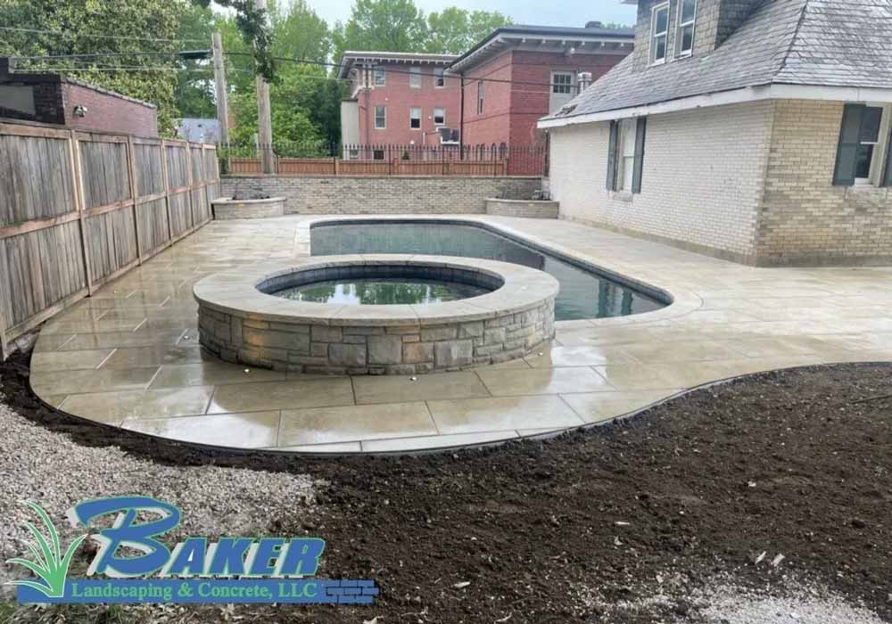 Round stone hot tub and rectangular pool on concrete patio
