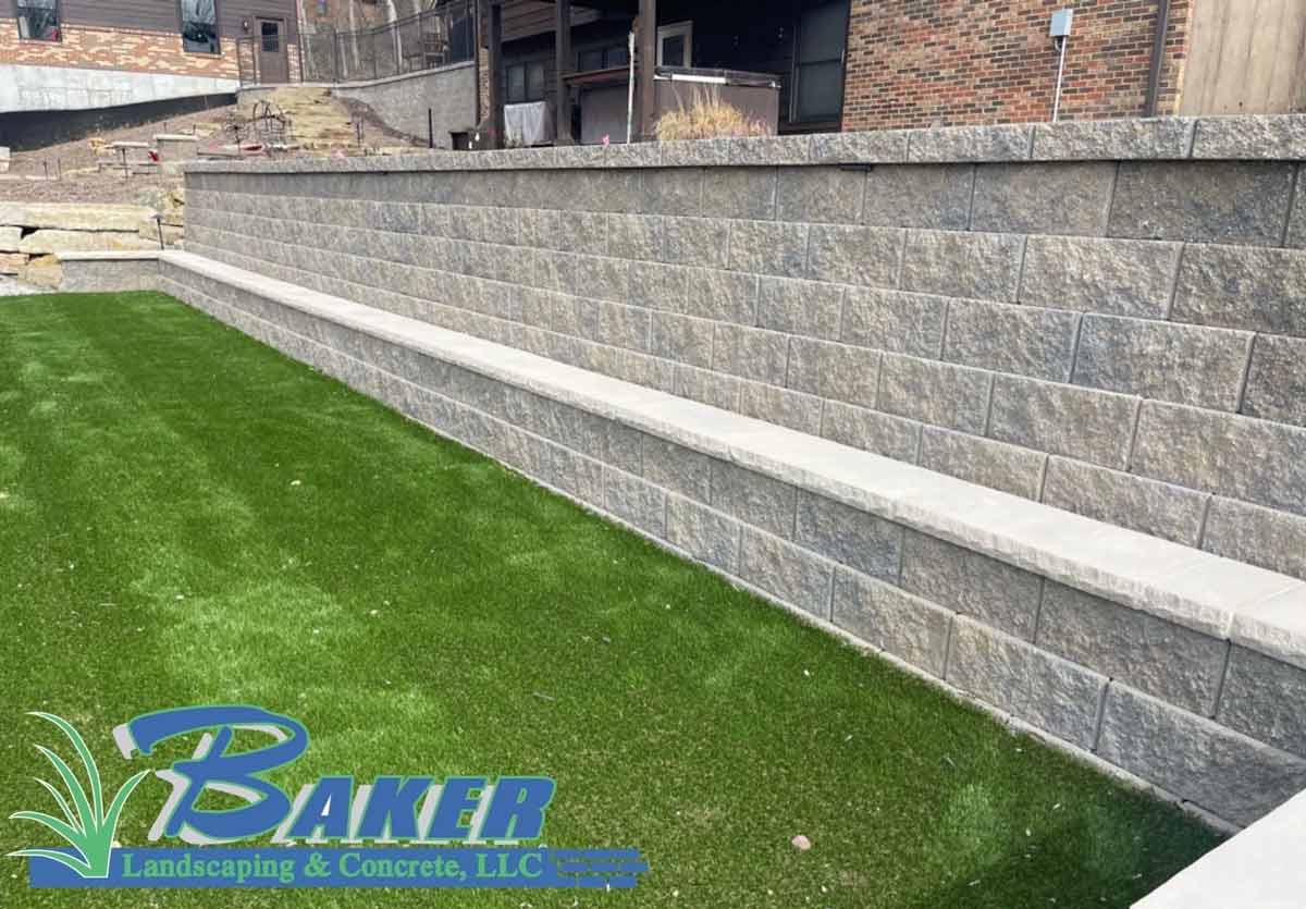 Stone retaining wall with a long concrete bench and artificial grass