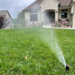 closeup of irrigation system sprinkler in front lawn of home