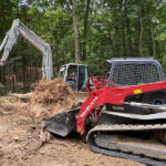 two excavators digging out the roots of tree in forest