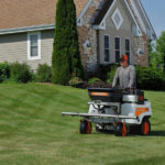 landscaper riding fertilization tractor on lawn